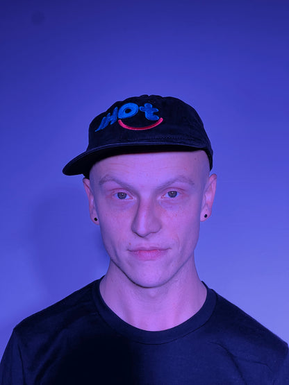 A young man with chiseled features, smiling and wearing the Isaac Hadden Organ Trio baseball cap.