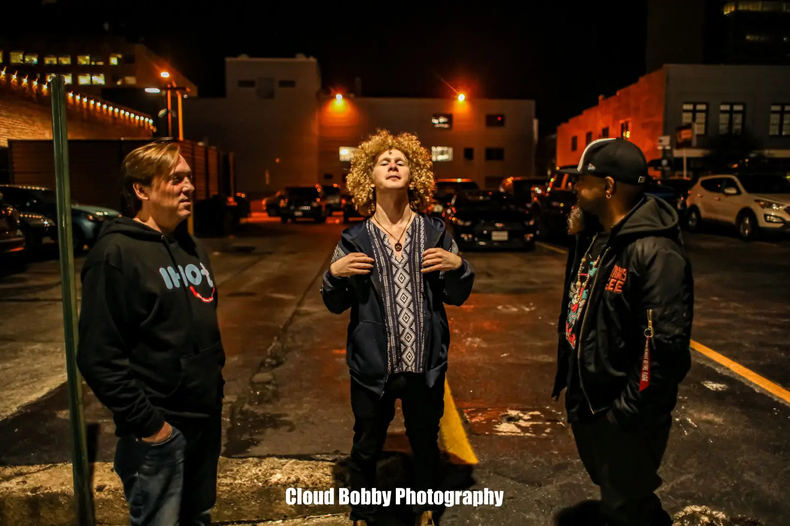 The Isaac Hadden Organ Trio standing in a Roanoke parking lot at night.