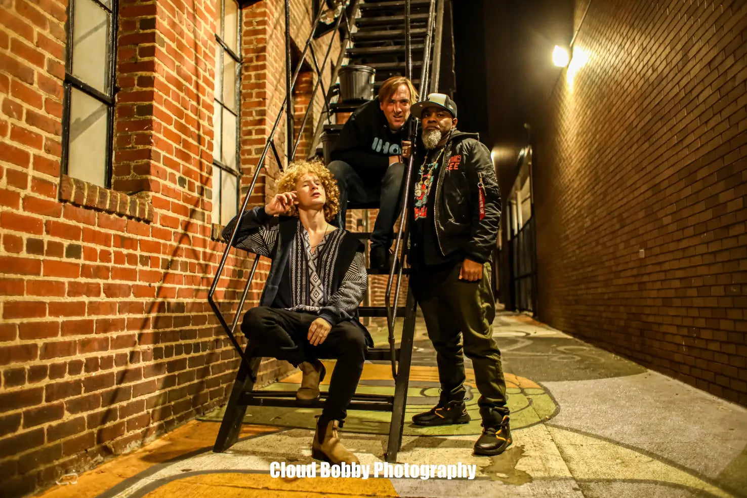 The Isaac Hadden Organ Trio posing for the camera in a back alley way under a street light.