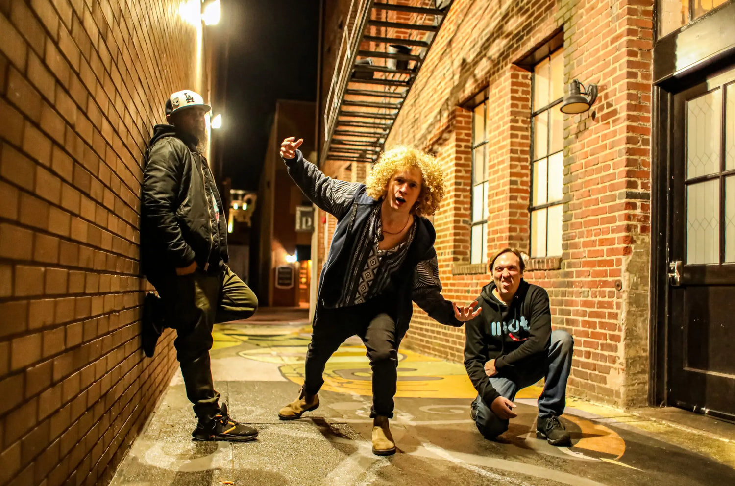 The Isaac Hadden Organ Trio posing for the camera in a back alley way under a street light.