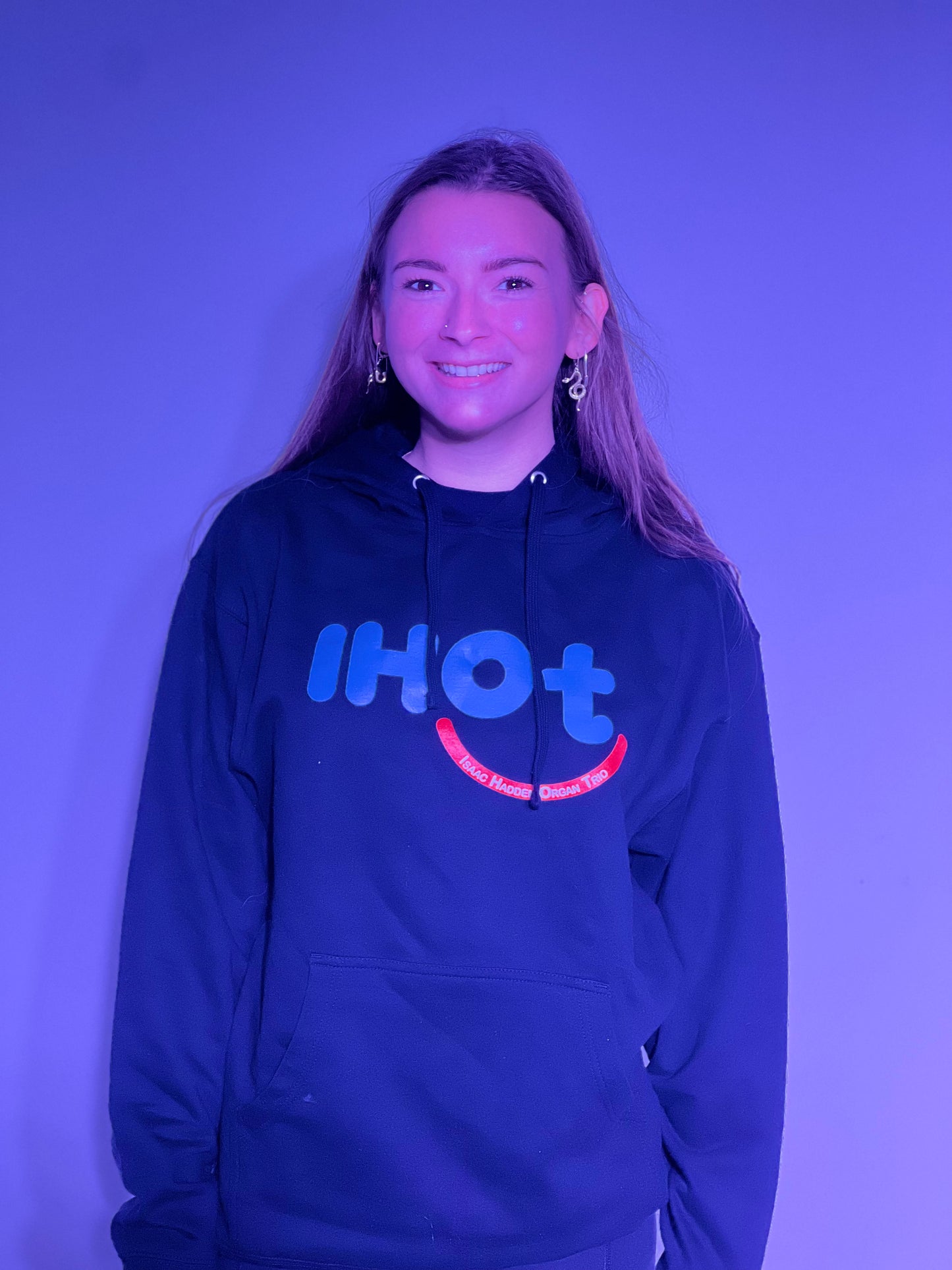 A young woman with brown hair and hazel eyes, smiling and wearing the Isaac Hadden Organ Trio black hoodie.